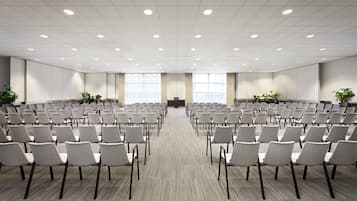 A conference room with rows of chairs, a podium, and large windows.