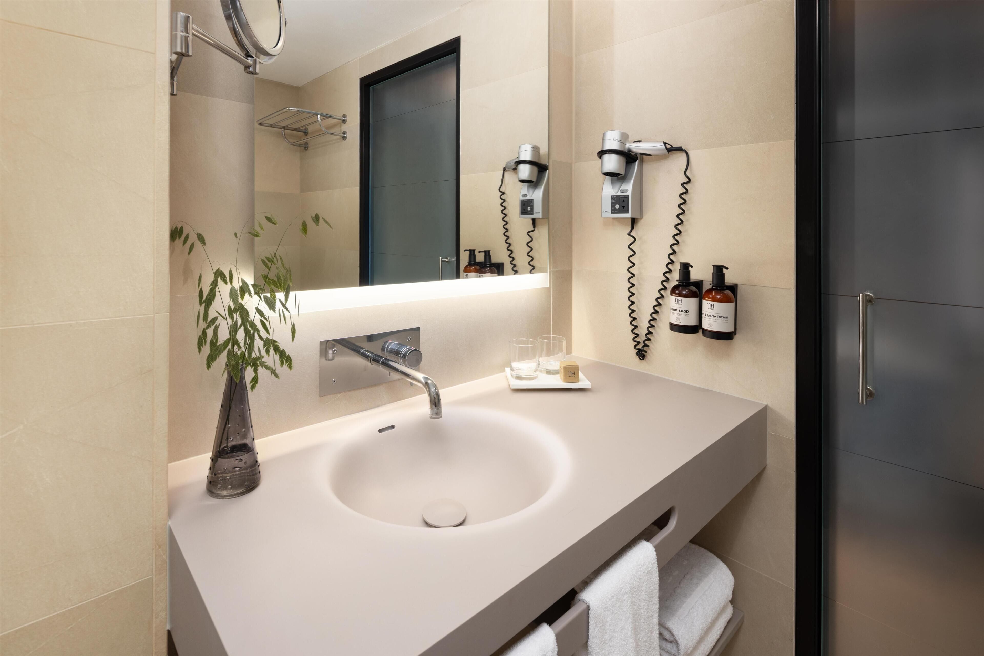 Un baño moderno con lavamanos, espejo y toallero.