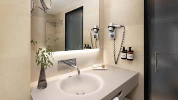 Un baño moderno con lavamanos, espejo y toallero.