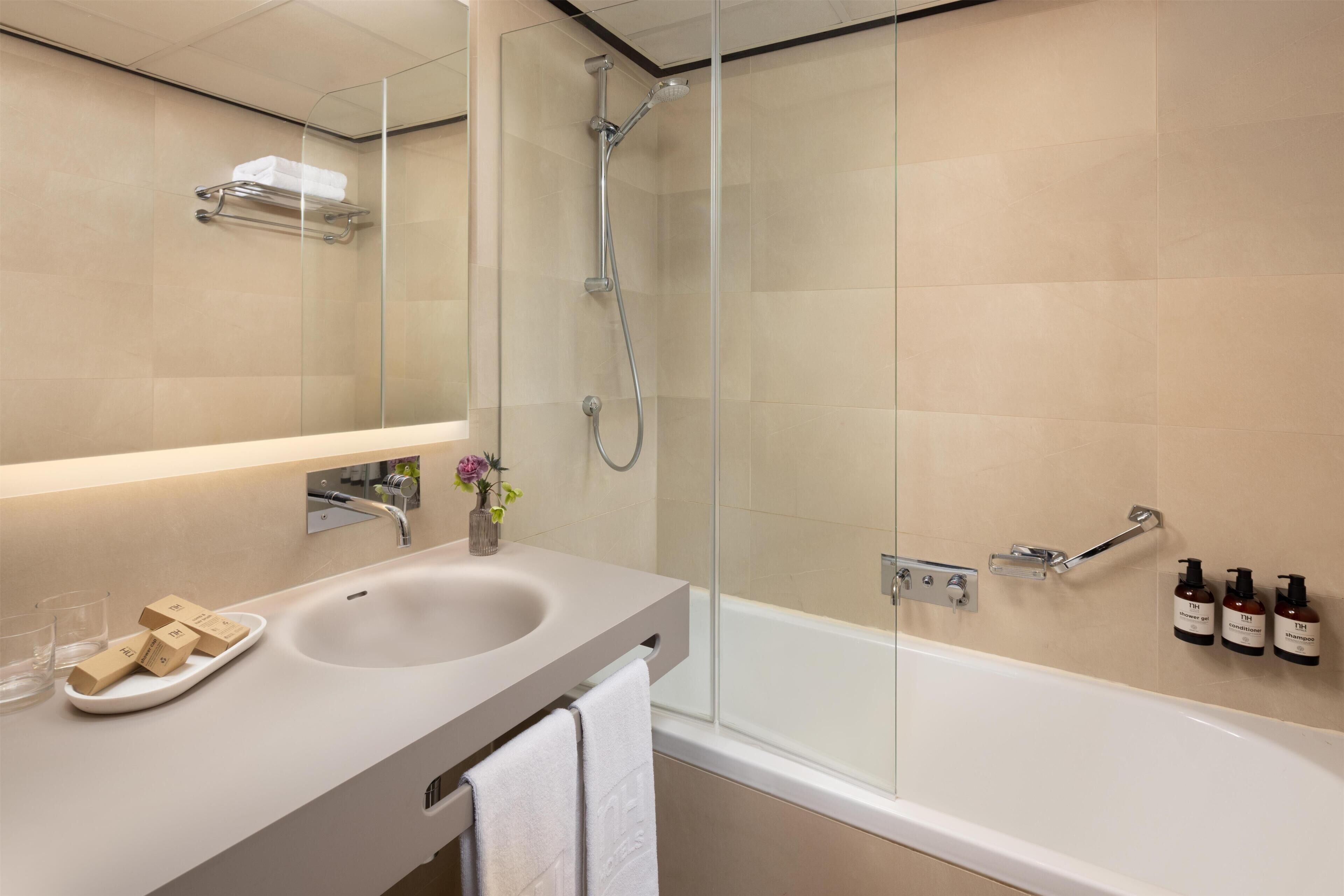 A modern bathroom with a glass-enclosed shower, a sink with a vanity, and toiletries on the wall.