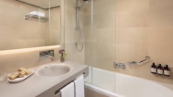 A modern bathroom with a glass-enclosed shower, a sink with a vanity, and toiletries on the wall.