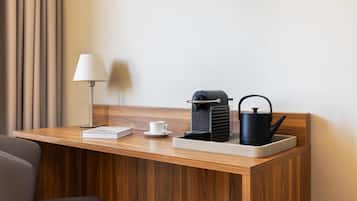 Uma mesa de madeira com uma lâmpada, uma cafeteira, uma xícara e um livro.