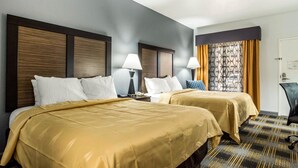 Ein Hotelzimmer mit zwei Betten, einem Schreibtisch und einem Stuhl.