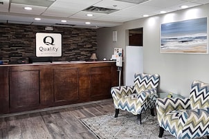 A reception area with a wooden reception desk, a patterned rug, and two patterned armchairs.