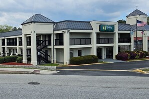 A multi-story hotel with a central entrance, a flag, and a sign for Quality Inn.