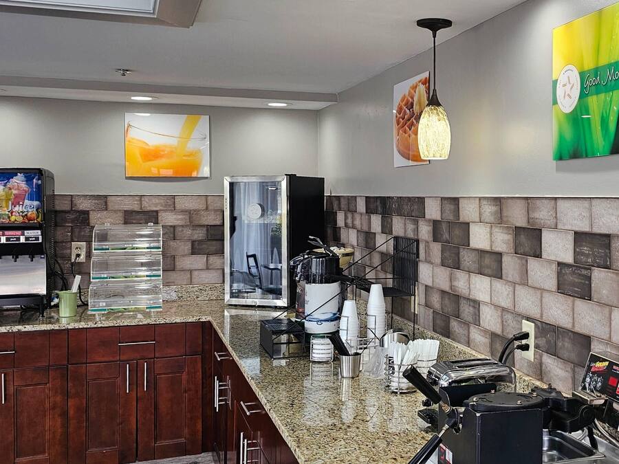 Un vestíbulo de hotel con una máquina de café, un dispensador de agua y un área de descanso con sillas y una mesa.