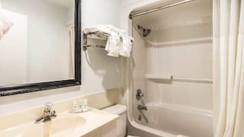 A bathroom with a sink, mirror, and a bathtub with a shower curtain.
