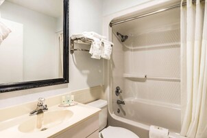 A bathroom with a sink, mirror, and a bathtub with a shower curtain.