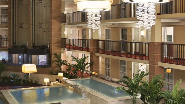 A multi-level hotel lobby with a central pool, multiple seating areas, and large chandeliers. - Embassy Suites by Hilton Cleveland Beachwood (Beachwood)