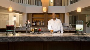 A bar area with a bartender, a wine cooler, and a well-stocked bar with various bottles and glasses. - Embassy Suites by Hilton Cleveland Beachwood (Beachwood)