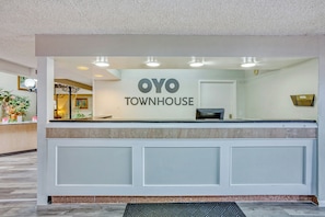 A reception desk with a sign reading 'OYO TOWNHOUSE'. - Garden Cove Hotel Suites (Tulsa)
