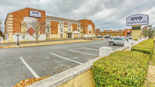 Un estacionamiento con un edificio identificado como 'OYO TOWNHOUSE', con fachada de ladrillo y varias ventanas.