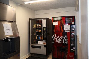 A vending machine area with snacks and a Coca-Cola machine. - Garden Cove Hotel Suites (Tulsa)