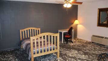 A bedroom with a wooden bed, a desk, a chair, a floor lamp, and a radiator.