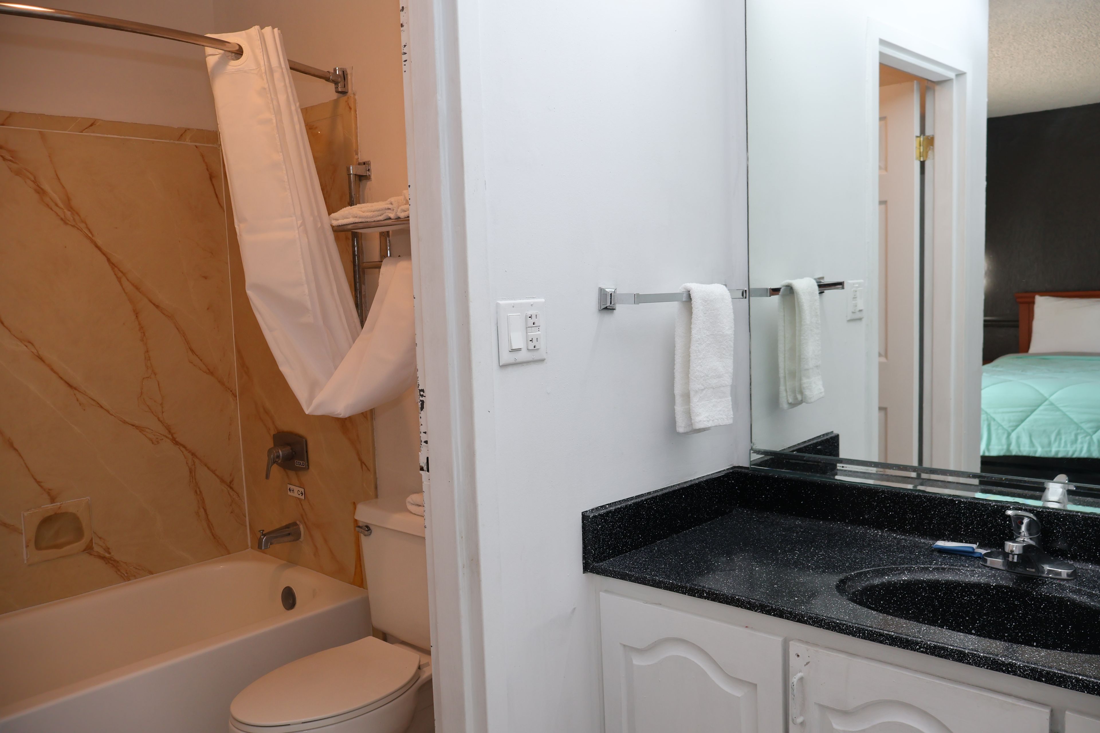 A bathroom with a bathtub, toilet, and a sink with a mirror.