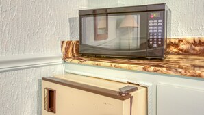 Un microondas sobre una encimera de mármol en una cocina con pared blanca y texturizada.
