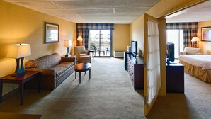 Una habitación de hotel con sofá, sillón, mesita, televisión y cama.