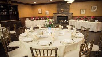 A banquet hall with round tables set for dining, featuring white tablecloths and gold chairs.