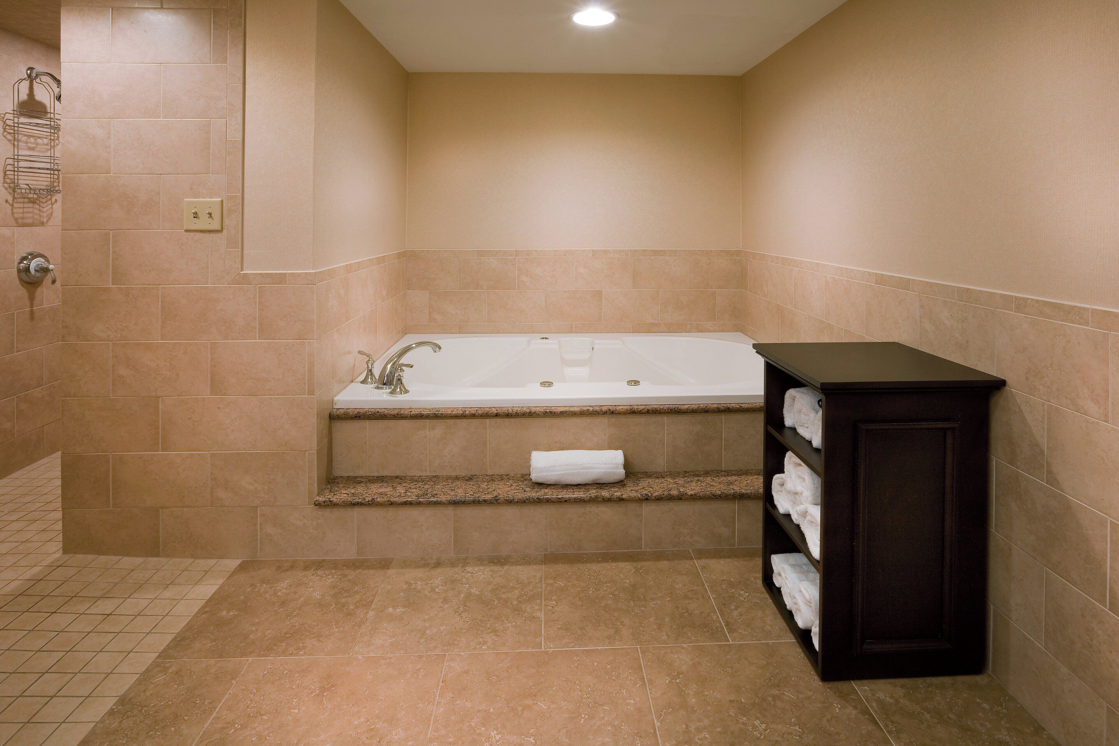 Une salle de bain avec une baignoire, un porte-serviettes et une étagère où sont rangées les serviettes.