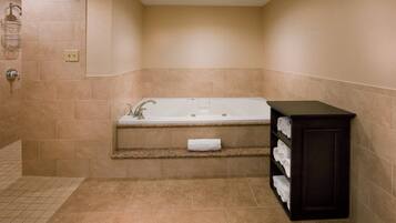 Une salle de bain avec une baignoire, un porte-serviettes et une étagère où sont rangées les serviettes.