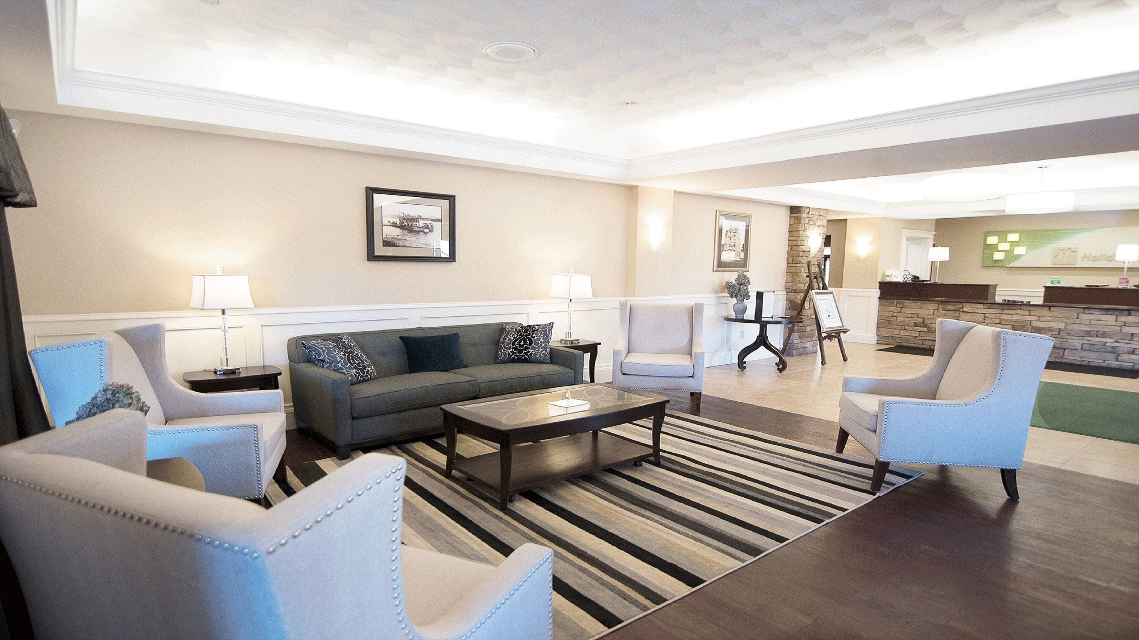 Een hotellobby met een zithoek, fauteuils, een salontafel en een receptiebalie.