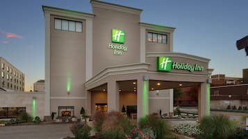 A Holiday Inn hotel with a modern facade, large windows, and a well-maintained garden area.