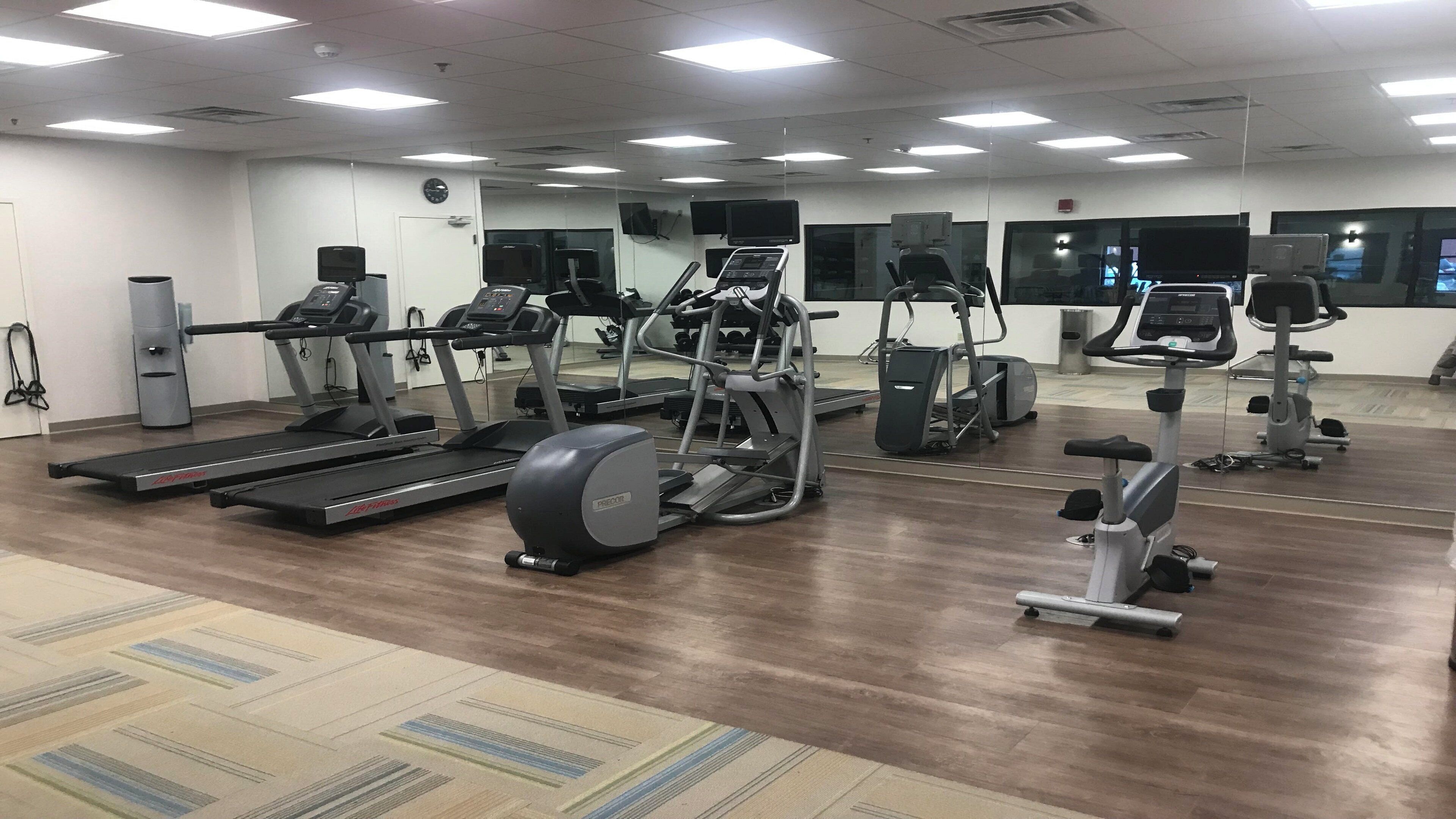 Un gimnasio con cintas de correr, elípticas y bicicletas estáticas.