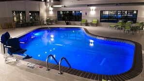 An indoor swimming pool with a clear water surface, surrounded by lounge chairs and a seating area with tables. - Holiday Inn Williamsport by IHG (Williamsport)