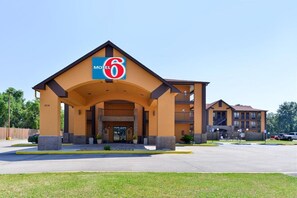 Edificio de Motel 6 con entrada destacada, estacionamiento y zona ajardinada.