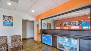 Un área de recepción con mostrador, sillas y carteles informativos.
