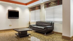 Una sala moderna con un sofá de cuero negro, una mesa de centro negra y un televisor de pantalla plana montado en la pared.