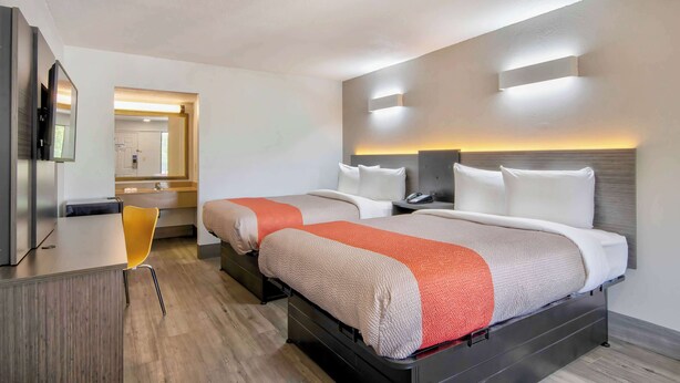 Habitación de hotel con dos camas, un escritorio y una silla.