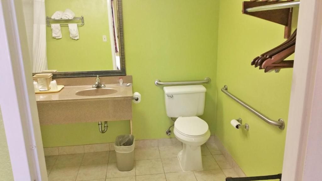 Une salle de bain équipée d’un lavabo, de toilettes et de barres d’appui.