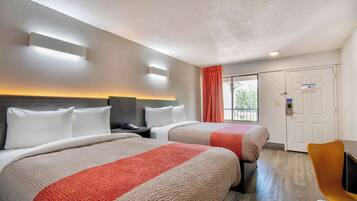 Une chambre d’hôtel avec deux lits, un bureau et une chaise.