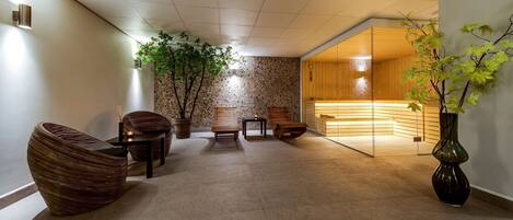A modern lobby with a stone wall, wooden benches, a large potted plant, and a reception area with a wooden counter.