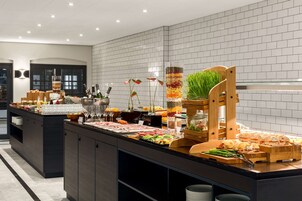 Un buffet proposant une variété de plats et de boissons, une chaise en bois et des plantes décoratives.