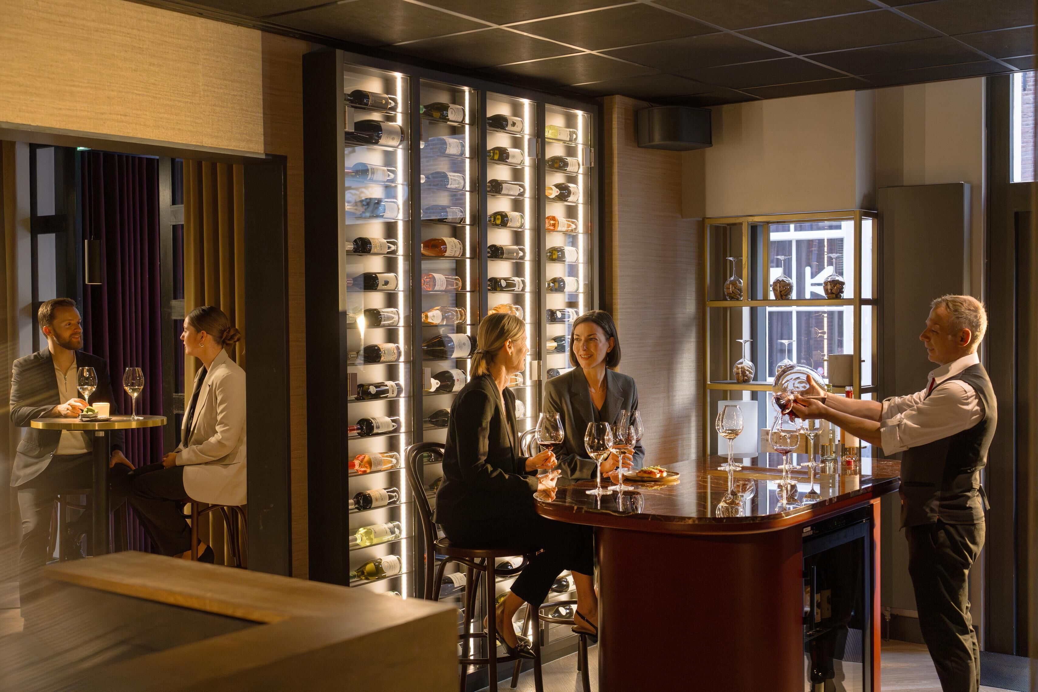 A bar area with a wine rack in the background and a bartender serving drinks.