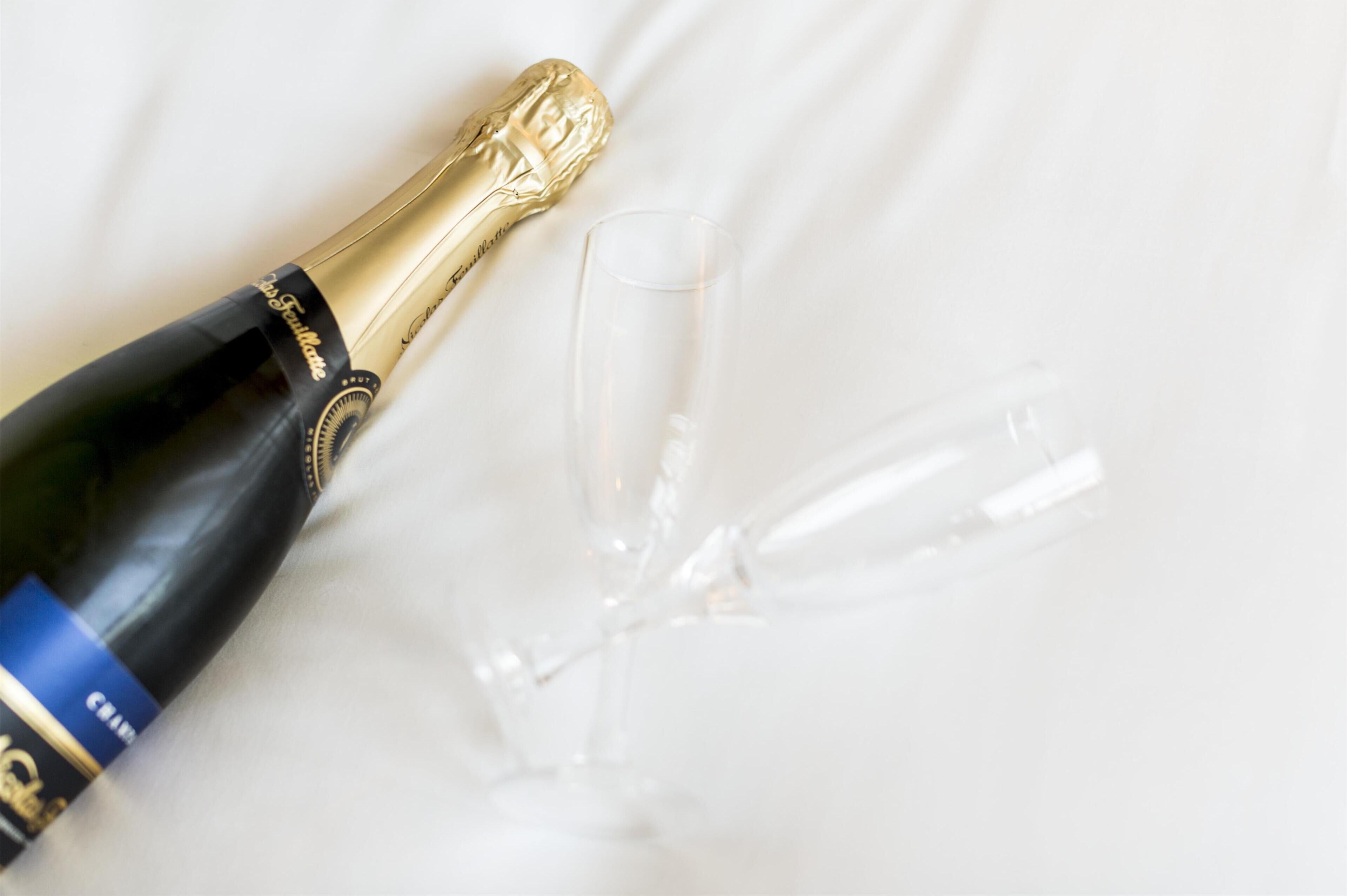 A champagne bottle and two empty glasses on a white surface.