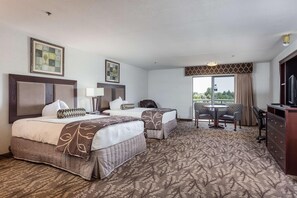 A hotel room with two beds, a desk, a chair, a TV, and a window with a view. - Shilo Inn Suites Idaho Falls (Idaho Falls)