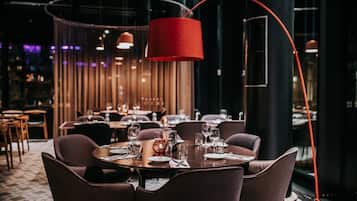 Un restaurante con mesas redondas, sillas marrones y una lámpara colgante roja.