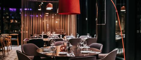 Un restaurante con mesas redondas, sillas marrones y una lámpara colgante roja.