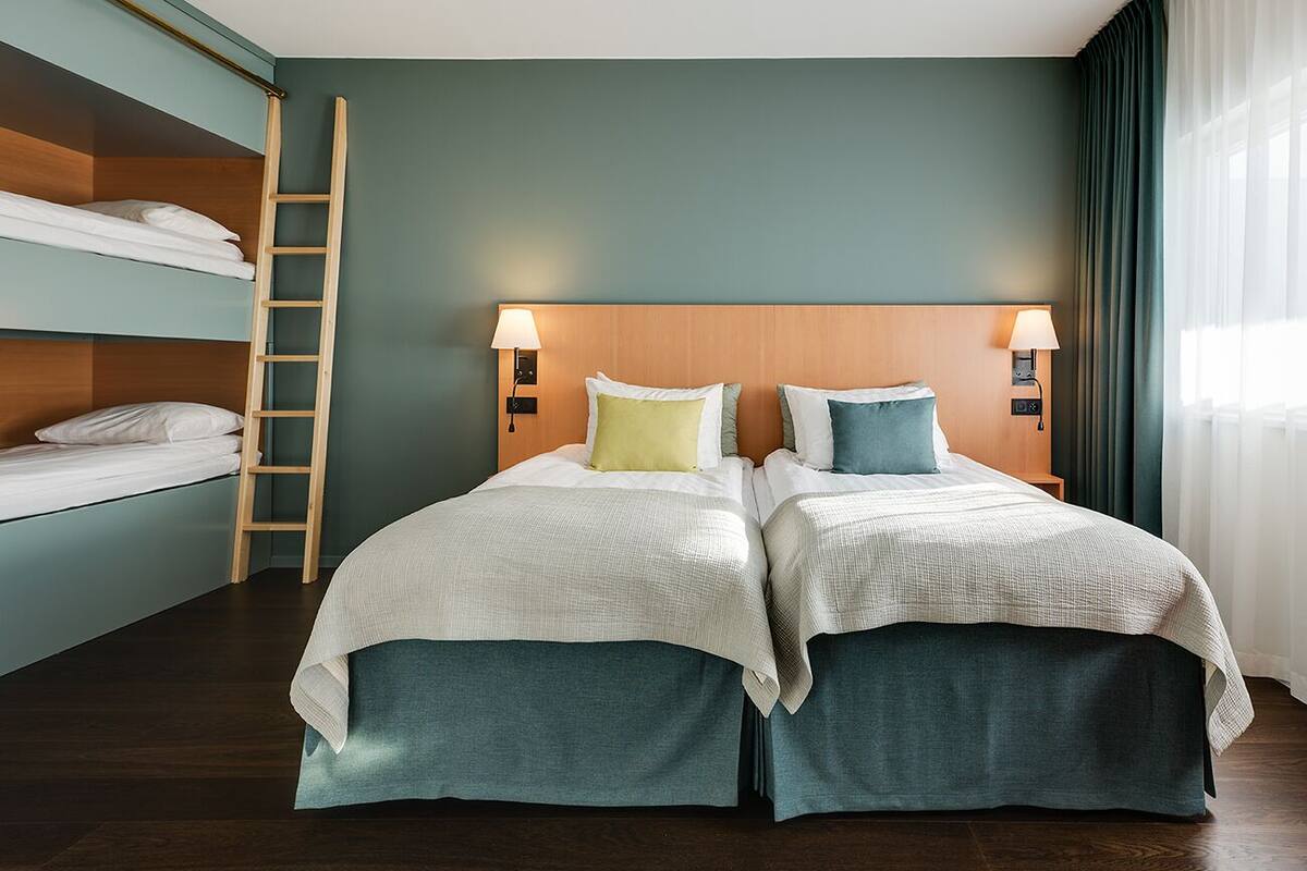 A hotel room with two beds, a wooden ladder, and two bedside lamps.