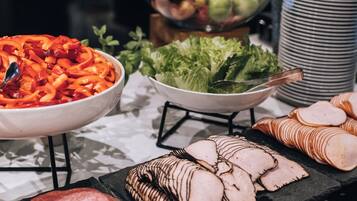 Un bufé con diversas opciones de comida, incluyendo carnes cortadas, queso y frutas.