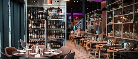 A restaurant with a wine cellar, dining tables, chairs, and shelves with glassware.