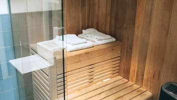 Una sauna con bancos de madera y una mampara de cristal.