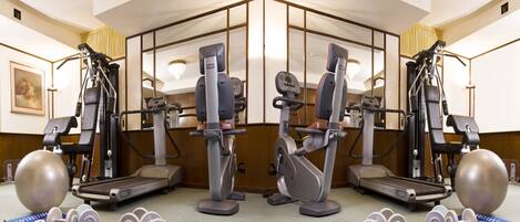 A gym with various exercise machines, dumbbells, and exercise balls.
