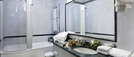 A modern bathroom with a glass-enclosed shower, a vanity with a sink and mirror, and a toilet with a trash can.