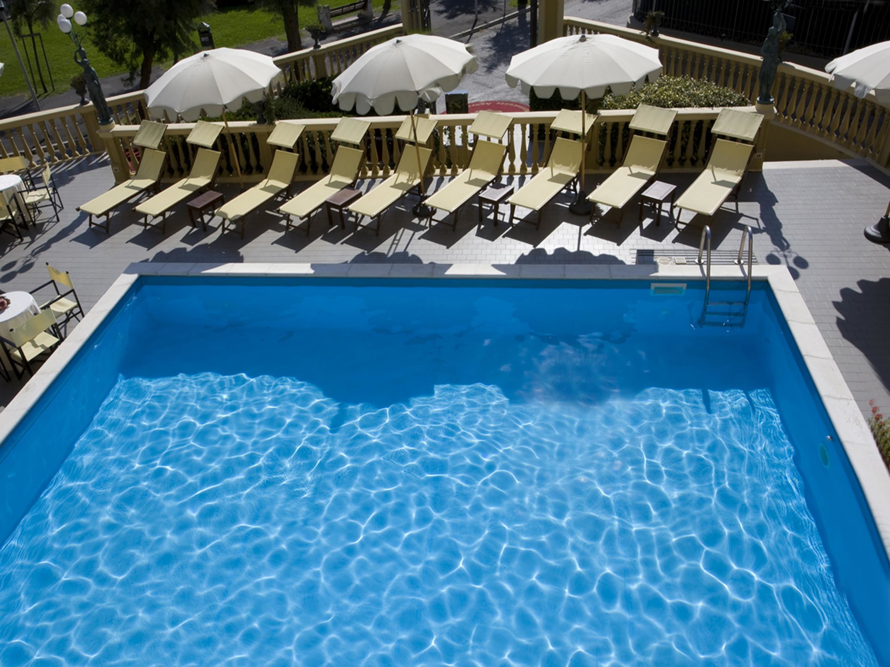A swimming pool with lounge chairs and umbrellas.