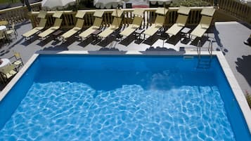 A swimming pool with lounge chairs and umbrellas.