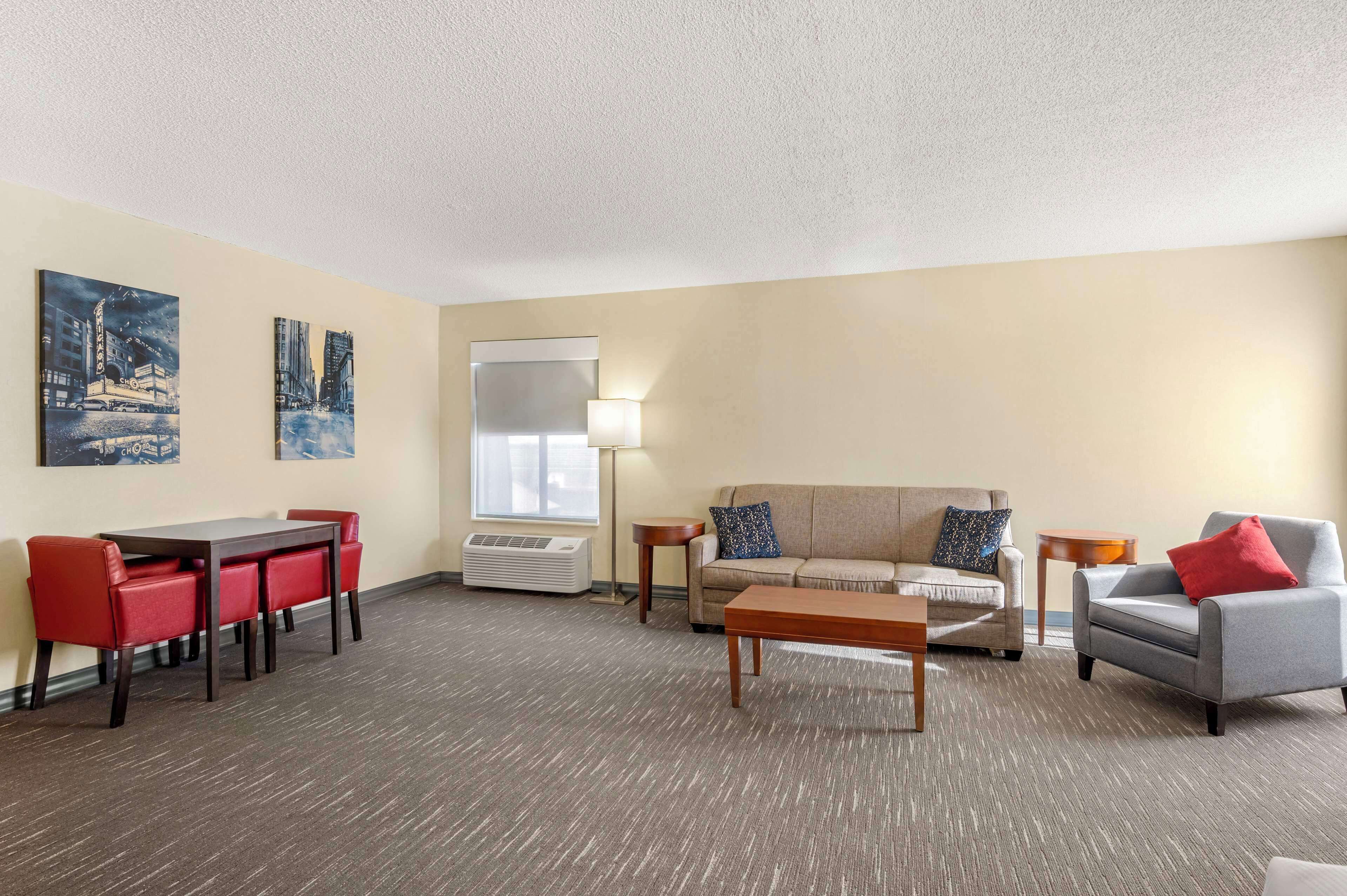 A hotel room with a dining area, a sofa, a coffee table, and two side tables.